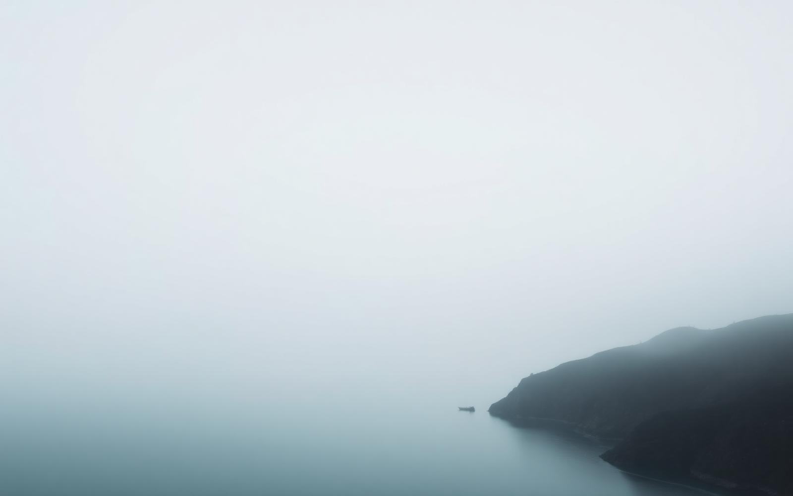Sea fog lifting off a still bay